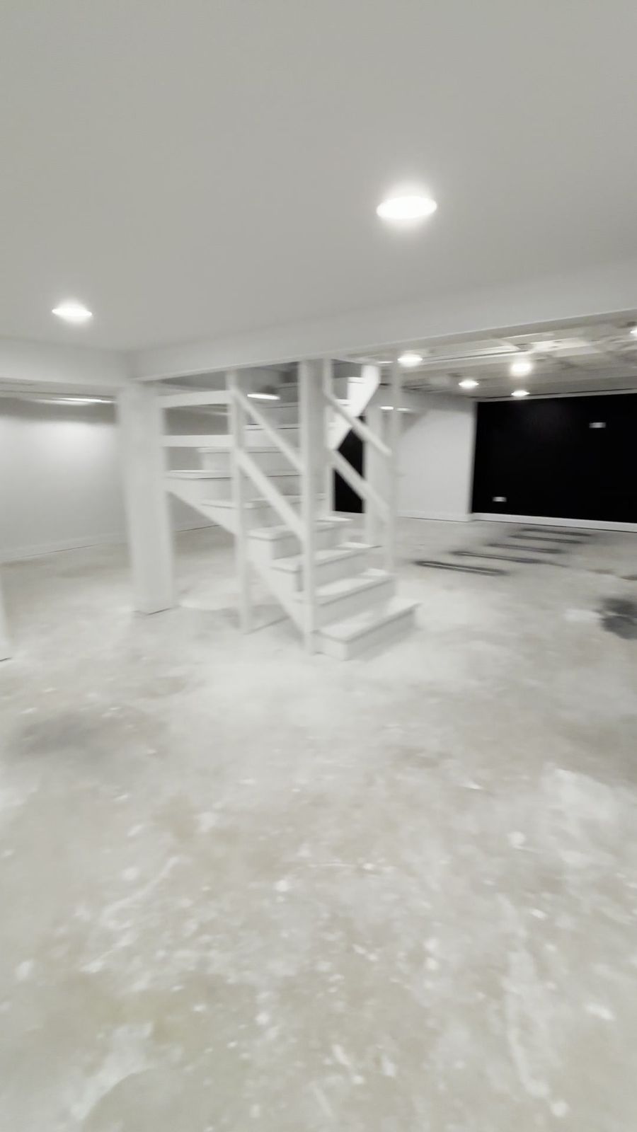 Finished basement with drywall, recessed lighting and a black accent wall
