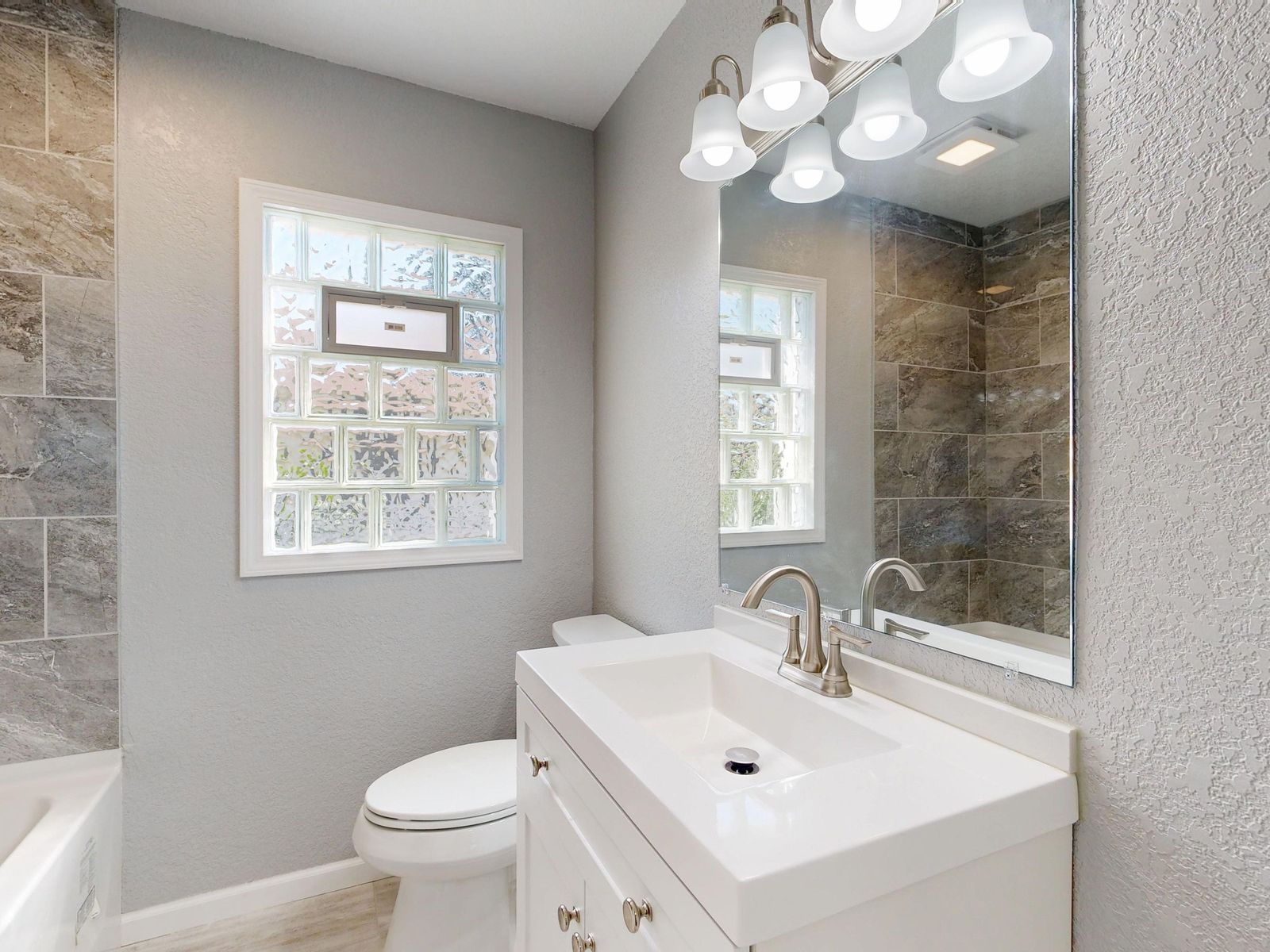 Complete remodeled bathroom with tiled shower, vanity and natural light