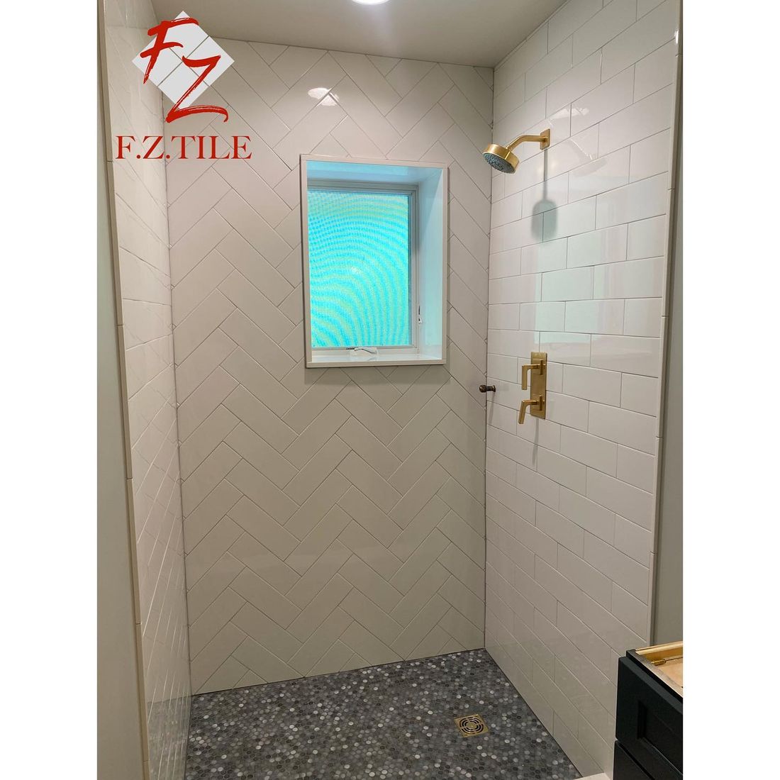 White herringbone shower with brass fixtures