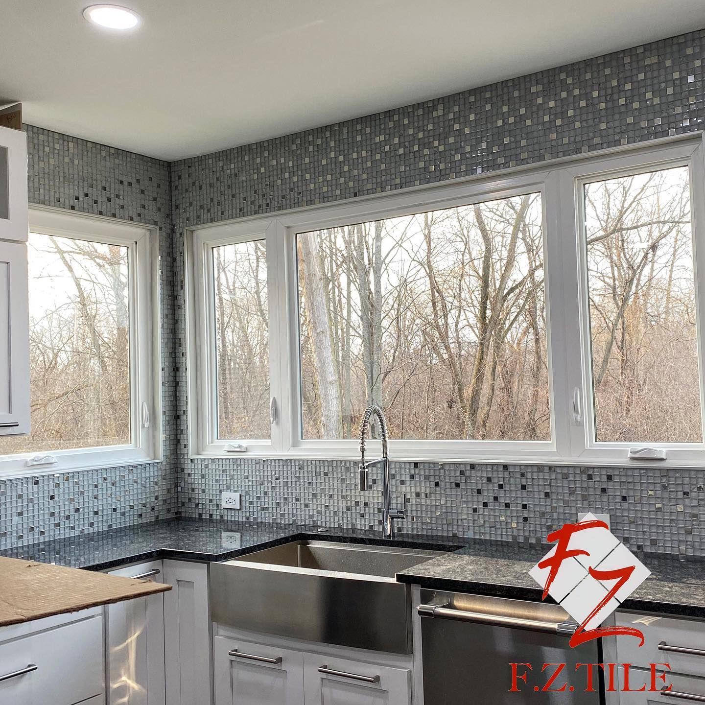 Kitchen mosaic backsplash with farmhouse sink and forest view