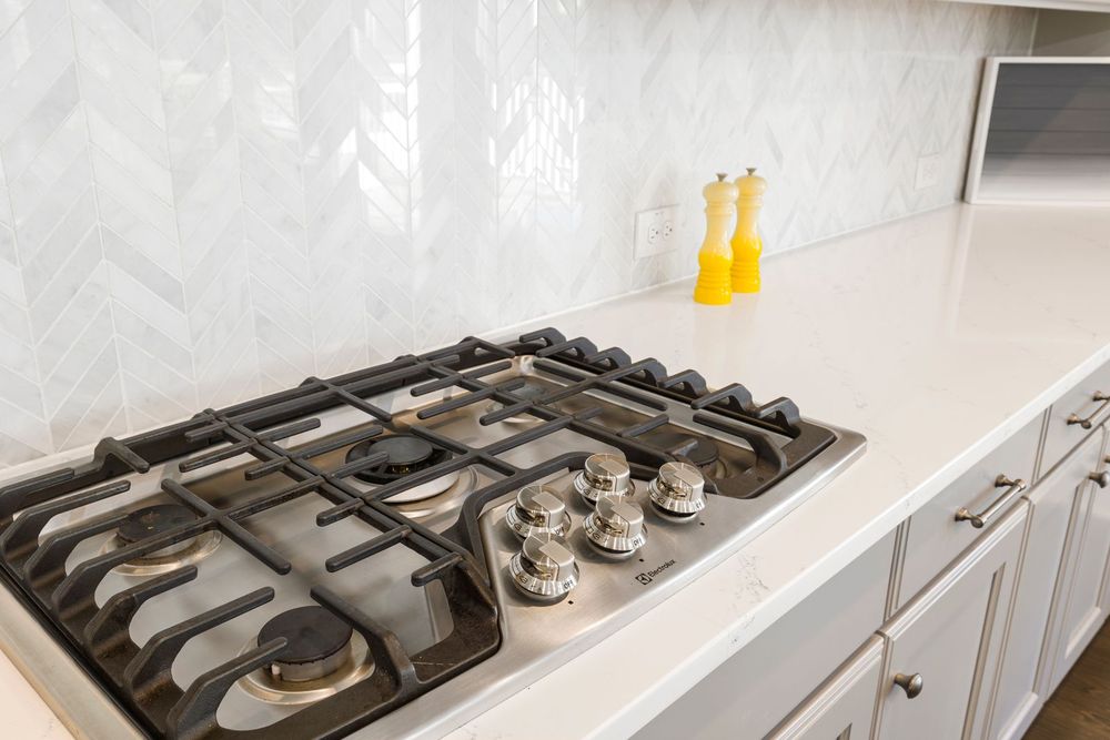White chevron kitchen backsplash behind a gas cooktop